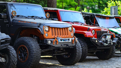 Close front view of an orange-and-black Jeep among several parked 4x4s.