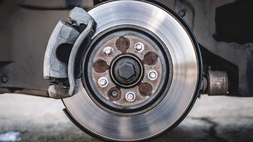 Detailed view of a vehicle’s front brake assembly on a lifted wheel hub.
