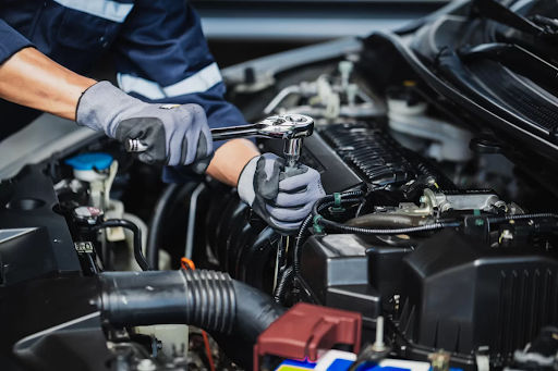 A mechanic using a wrench to repair an engine in a workshop, working on a car’s engine components.