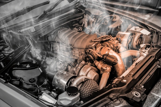 A car engine emitting smoke, indicating an overheating or mechanical issue.