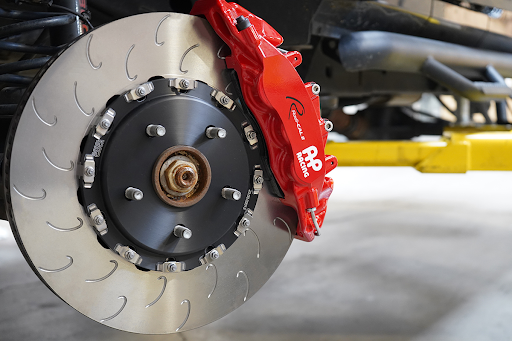 A close-up of a high-performance brake system with red brake calipers and drilled brake disc mounted on a vehicle.